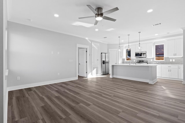 unfurnished living room with visible vents, ornamental molding, ceiling fan, wood finished floors, and baseboards