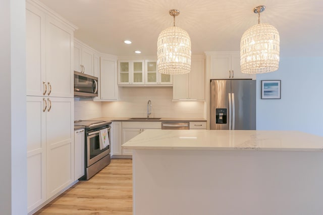 kitchen featuring sink, white cabinetry, stainless steel appliances, and an inviting chandelier