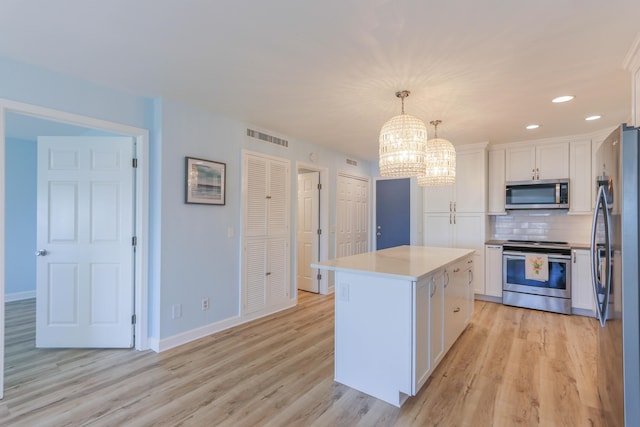 kitchen with a center island, tasteful backsplash, pendant lighting, white cabinets, and appliances with stainless steel finishes