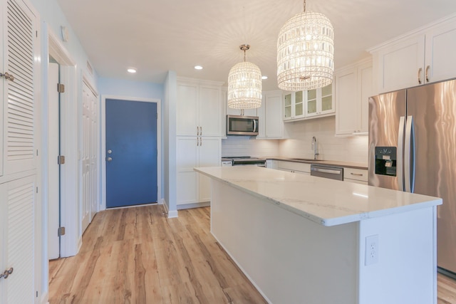 kitchen with a center island, decorative light fixtures, a notable chandelier, white cabinetry, and stainless steel appliances