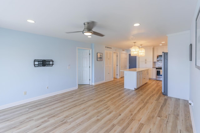 kitchen with stainless steel appliances, a kitchen island, decorative light fixtures, white cabinets, and ceiling fan with notable chandelier