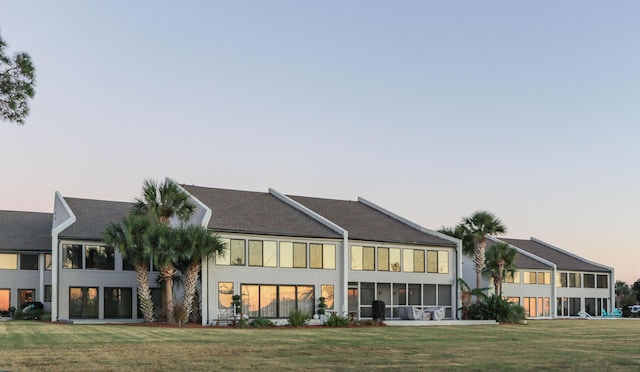 back house at dusk with a lawn