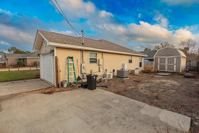 rear view of house with central AC, a storage unit, ac unit, and a garage