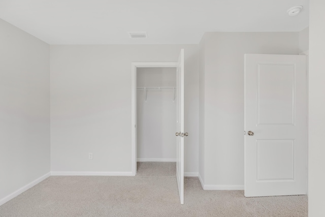 unfurnished bedroom with light colored carpet and a closet