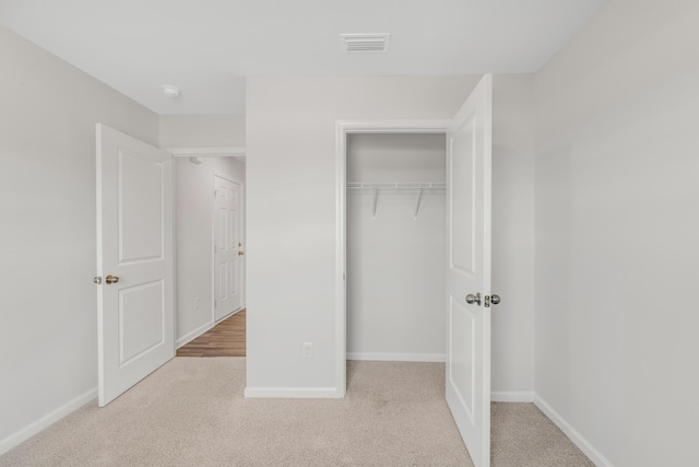 unfurnished bedroom with light colored carpet and a closet