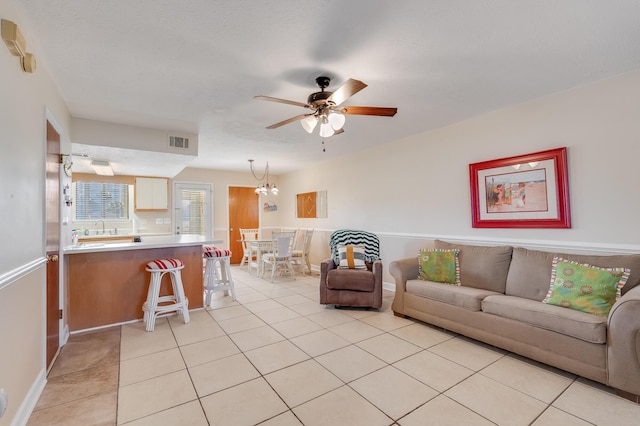 tiled living room featuring ceiling fan with notable chandelier