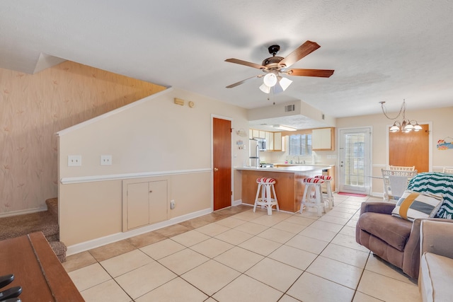 living room with light tile patterned flooring and ceiling fan with notable chandelier