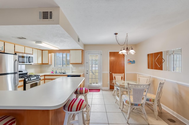 kitchen featuring sink, a notable chandelier, decorative light fixtures, light tile patterned floors, and appliances with stainless steel finishes