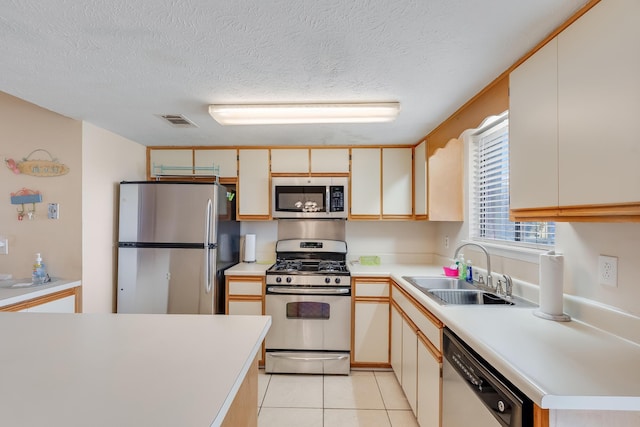 kitchen with a textured ceiling, light tile patterned flooring, sink, and appliances with stainless steel finishes