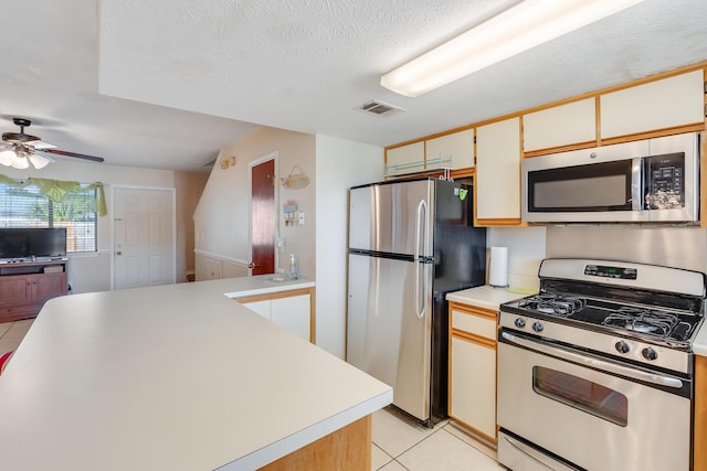 kitchen featuring ceiling fan, white cabinets, a textured ceiling, light tile patterned floors, and appliances with stainless steel finishes