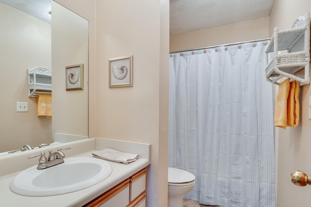 bathroom with vanity, toilet, a textured ceiling, and walk in shower