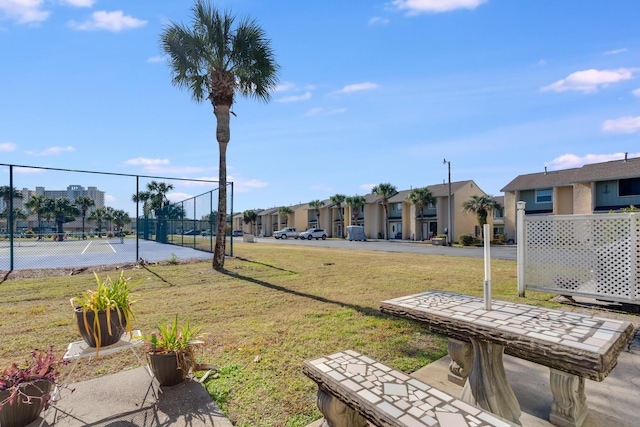 surrounding community featuring tennis court and a lawn