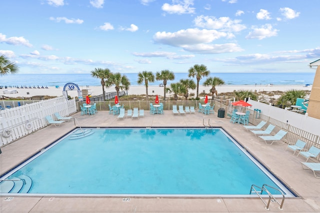 view of swimming pool featuring a view of the beach, a water view, and a patio area