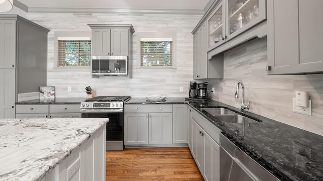 kitchen with dark stone countertops, sink, appliances with stainless steel finishes, and light hardwood / wood-style flooring