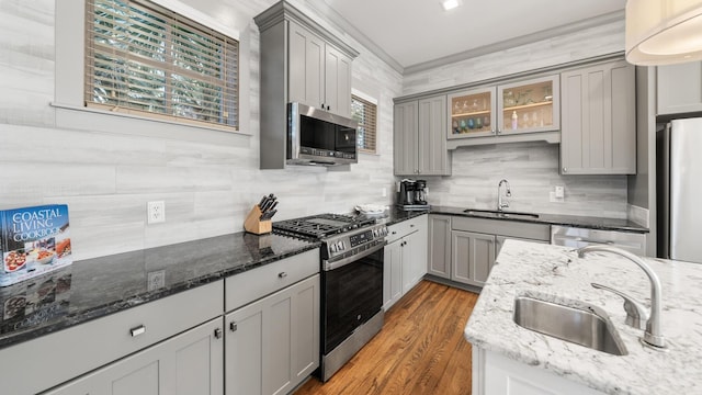 kitchen featuring gray cabinetry, sink, dark stone counters, appliances with stainless steel finishes, and ornamental molding