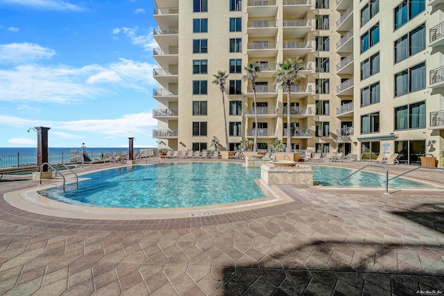 view of swimming pool with a water view and a patio area