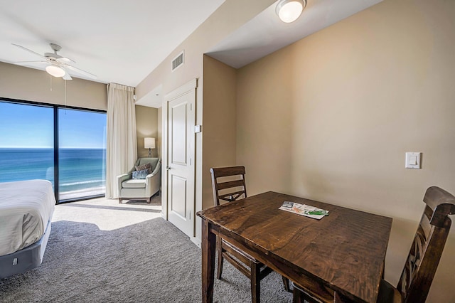 dining space featuring ceiling fan, a water view, and carpet floors