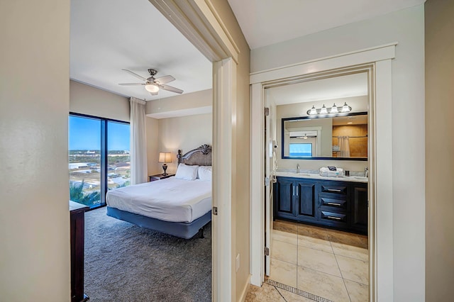 carpeted bedroom with ensuite bathroom, ceiling fan, and sink