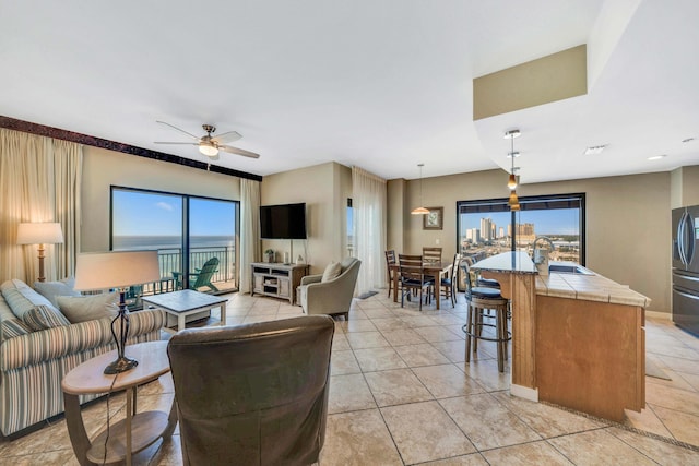 living room with ceiling fan, sink, light tile patterned flooring, and a healthy amount of sunlight