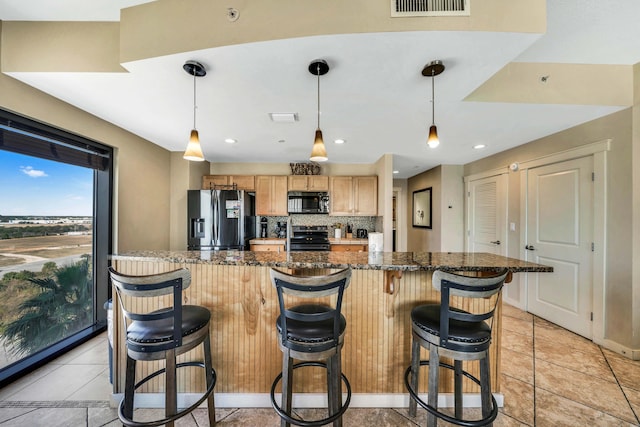 kitchen with decorative light fixtures, light tile patterned floors, and appliances with stainless steel finishes