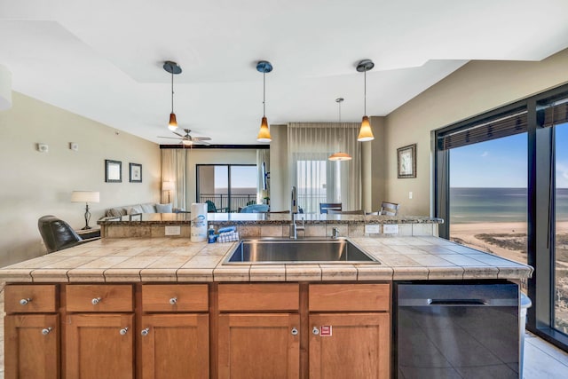 kitchen featuring ceiling fan, dishwasher, sink, and an island with sink