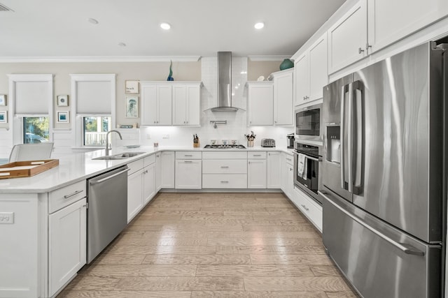 kitchen featuring white cabinetry, crown molding, wall chimney range hood, and stainless steel appliances