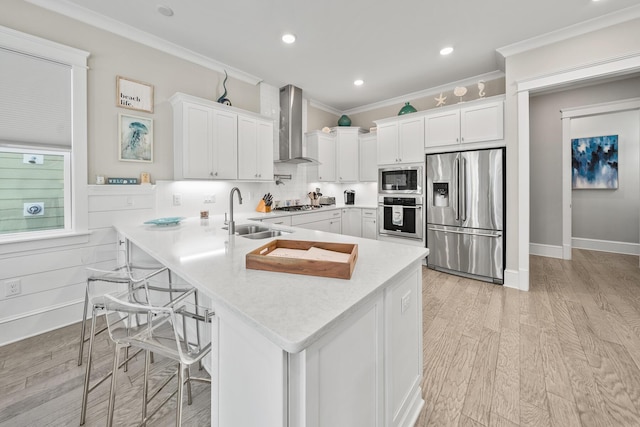 kitchen with sink, wall chimney exhaust hood, kitchen peninsula, white cabinets, and appliances with stainless steel finishes