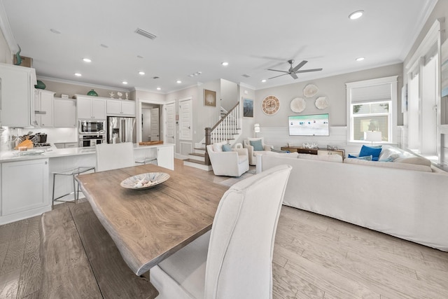 dining space featuring ceiling fan, crown molding, and light wood-type flooring