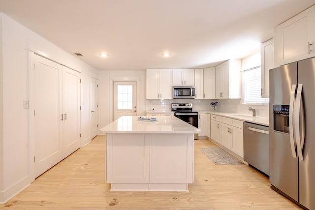 kitchen featuring white cabinets, plenty of natural light, a kitchen island, and stainless steel appliances