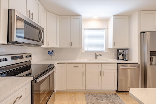 kitchen with white cabinets, sink, light wood-type flooring, and stainless steel appliances