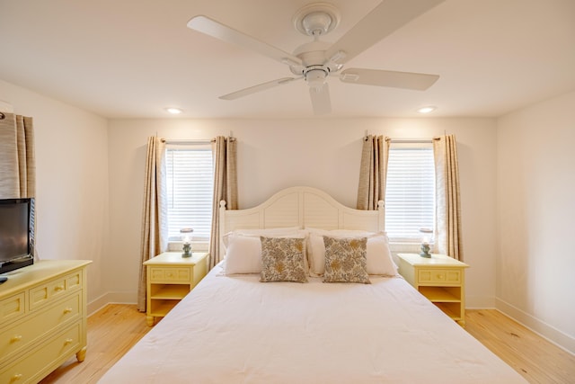 bedroom featuring ceiling fan, light hardwood / wood-style flooring, and multiple windows