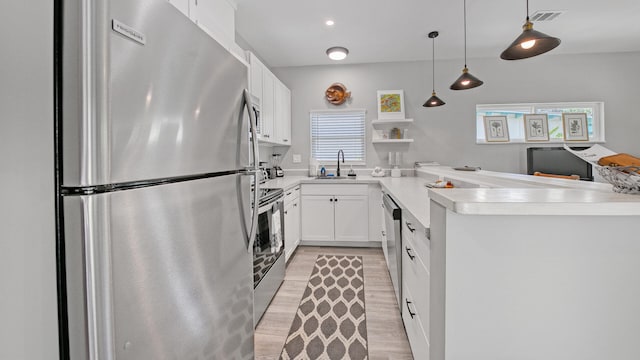 kitchen featuring white cabinetry, sink, stainless steel appliances, kitchen peninsula, and pendant lighting