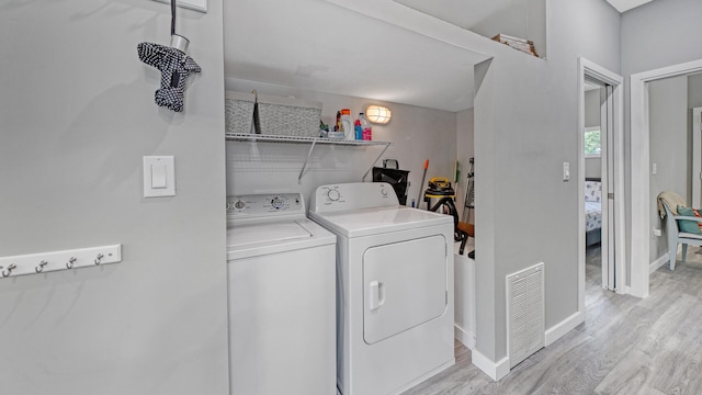 laundry room featuring light wood-type flooring and separate washer and dryer