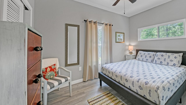 bedroom with ceiling fan, light hardwood / wood-style floors, and multiple windows