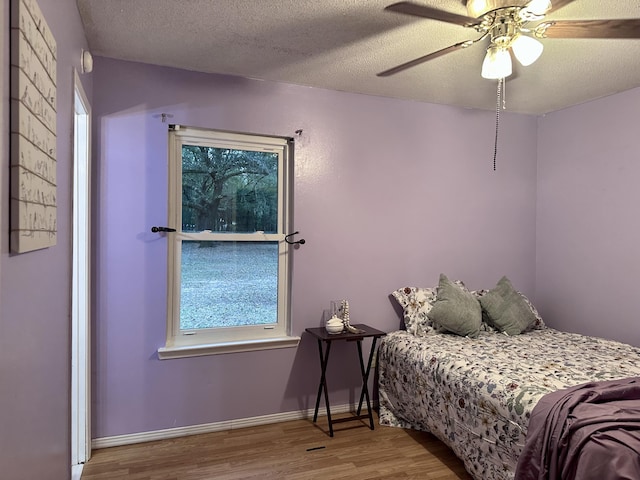 bedroom featuring ceiling fan, light hardwood / wood-style floors, and a textured ceiling