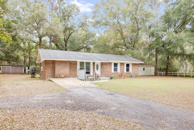 ranch-style house featuring a storage shed and a front lawn