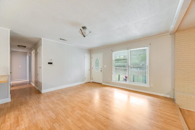 unfurnished room featuring a fireplace, light hardwood / wood-style floors, a textured ceiling, and ornamental molding