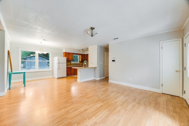 unfurnished living room with a chandelier, crown molding, a textured ceiling, and light hardwood / wood-style flooring