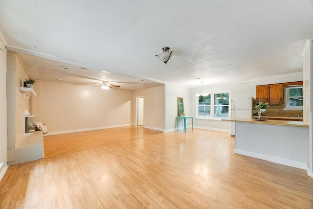 unfurnished living room with a textured ceiling, ceiling fan, light hardwood / wood-style floors, and a fireplace