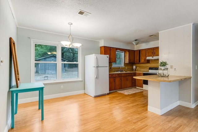 kitchen with kitchen peninsula, light wood-type flooring, white appliances, a notable chandelier, and hanging light fixtures