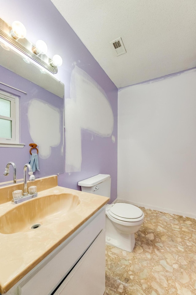 bathroom featuring vanity, a textured ceiling, and toilet