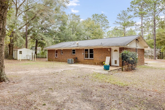 rear view of property with central AC unit and a storage unit