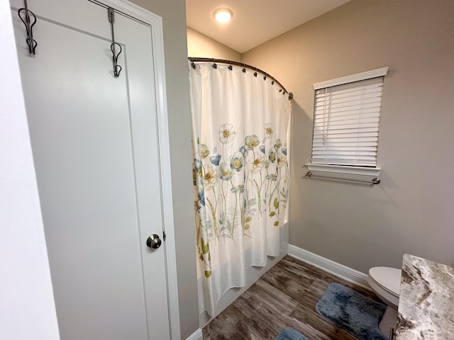 bathroom with shower / bath combo with shower curtain, wood-type flooring, and toilet