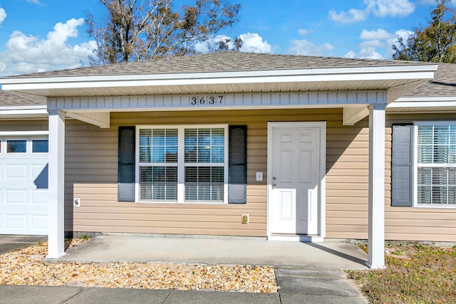 doorway to property with covered porch and a garage