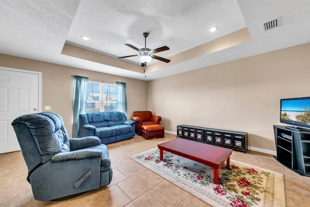 tiled living room featuring a textured ceiling, a tray ceiling, and ceiling fan