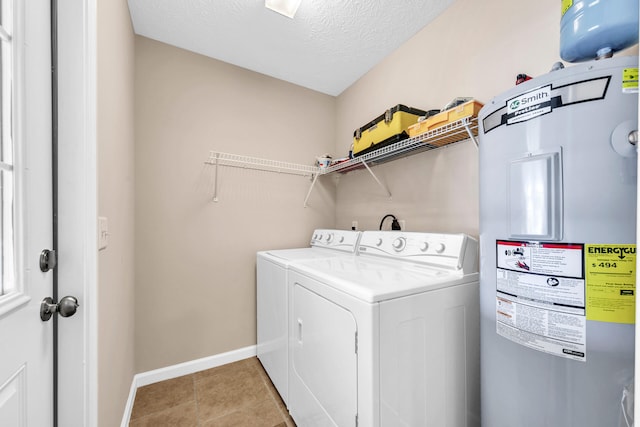 washroom featuring light tile patterned flooring, a textured ceiling, washing machine and dryer, and water heater