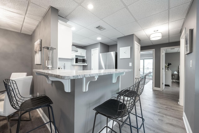 kitchen with kitchen peninsula, white cabinetry, a breakfast bar area, and stainless steel appliances