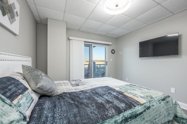 bedroom featuring a drop ceiling and access to outside