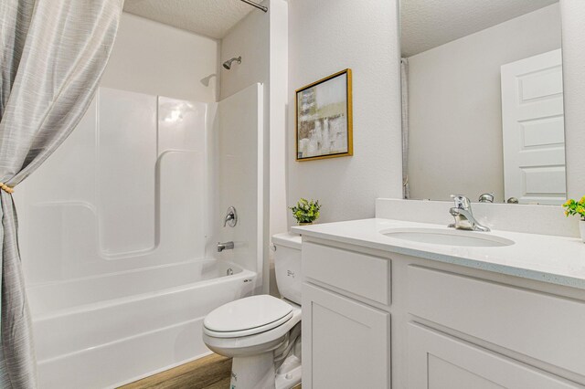 full bathroom featuring shower / bath combination with curtain, vanity, a textured ceiling, hardwood / wood-style floors, and toilet