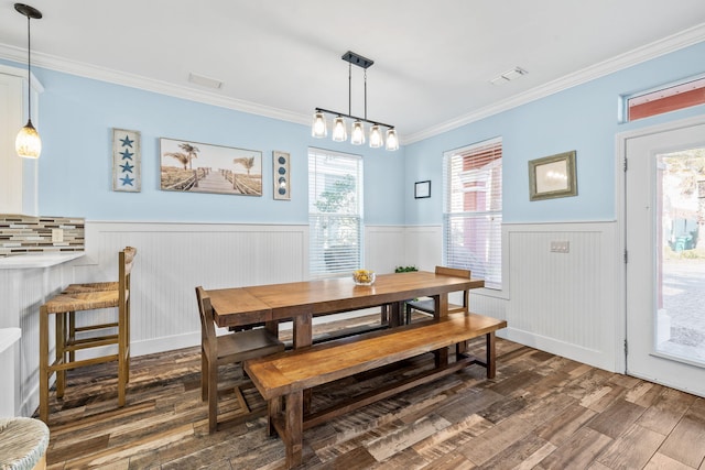 dining room featuring wainscoting, wood finished floors, visible vents, and crown molding